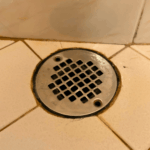 Professional plumber using drain auger tool to clear a shower drain clog in West Valley City.