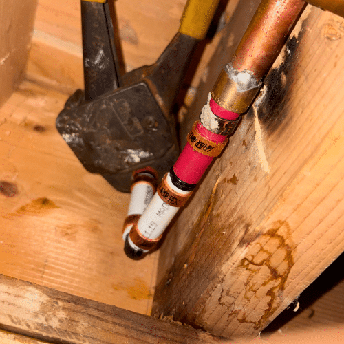 Active leak found on red PEX water line causing moisture damage to wood framing inside a Millcreek wall cavity.