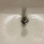 Inspecting the sink drain wall arm and venting connection during a West Jordan plumbing repair.