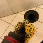 Professional plumber using drain auger tool to clear a shower drain clog in West Valley City.