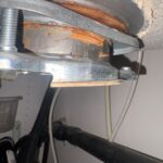 Close-up of corroded metal garbage disposal mounting bracket and gasket area under the sink flange in Salt Lake City.