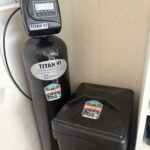 Black Titan VI softener tank and brine tank installed with bypass valves after Millcreek water softener replacement by Mountain Man Plumbing.