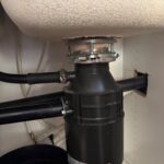 Garbage disposal reseated on a fresh metal mounting bracket under the sink after leak repair in Salt Lake City Utah.