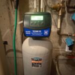 Titan VI conditioner display in rinse cycle beside brass PRV on Park City basement wall