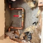 Completed copper main with new red-handle ball valve in wall opening after Salt Lake City replacement