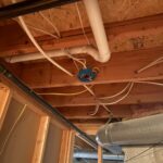 Open basement ceiling joists with plumbing runs visible before finish work during poly pipe upgrade Sandy