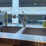 Chrome pull-out kitchen faucet centered on stainless double sink after fixture replacement