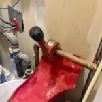 Ridgid pipe cutter on copper tubing over red drip tray in mechanical closet during install