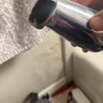 Close view of damaged chrome tub spout outlet and markings held by technician after removal in Salt Lake City