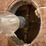 Drain cleaning cable entering a floor access hole toward bathroom piping in Millcreek Utah.