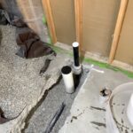 New vertical drain stubs set in cut slab for laundry and kitchen rough-in work in a Draper basement remodel.