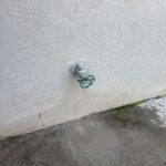 Old metal outdoor hose bib with green handle on stucco wall before replacement in Draper Utah