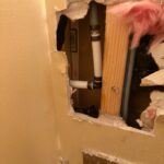 Interior wall opening showing polybutylene supply piping and fittings during hose bib access in Draper