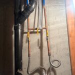 Supported copper bypass with yellow valves feeding stainless flex connectors to the softener inlets on a Draper basement wall.