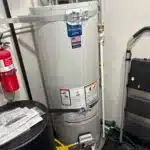 Side view of installed Bradford White tank showing gas control, yellow flex line, drain, and relief piping in North Salt Lake.