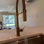 Customer kitchen faucet running a clear stream into stainless sink after Midway installation work