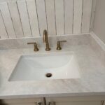 Brass widespread bathroom faucet with separate handles on marble vanity sink installed in Midway Utah