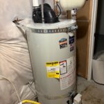 Installed power vent tank with expansion tank, flexible water lines, yellow gas shutoff, and EnergyGuide label in South Jordan