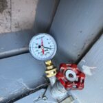 Outdoor faucet with red handle and pressure gauge reading during Millcreek Utah plumbing diagnostics.