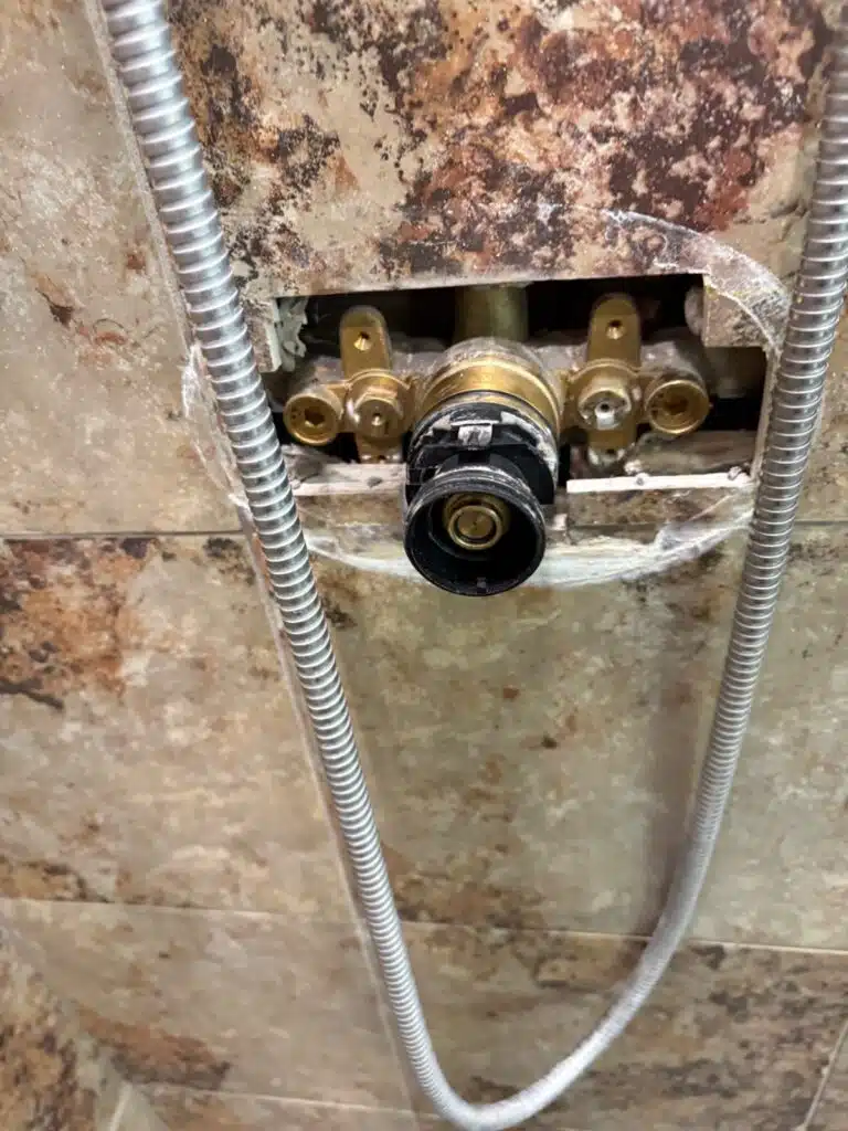 Black valve housing opened on a brass Grohe body during a shower repair in Sandy, Utah