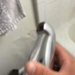 Plumber holding removed chrome tub spout showing wear at the outlet during Salt Lake City diverter repair