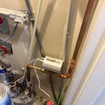 Resideo auto shutoff valve on copper pipe with green indicators in condo utility corner