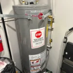 Old Rheem Performance Plus still strapped in the utility closet with STOP warranty label before North Salt Lake removal.