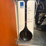 White under-sink reverse osmosis tank with temperature display inside open kitchen cabinet