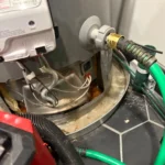 Rust and standing water in the pan under the failing water heater base before removal in North Salt Lake.