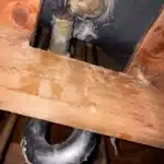 Corroded tub shoe and wet wood with old trap below floor before removal Salt Lake City