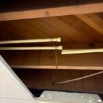 Cut cream plastic water lines hanging under wood joists after isolation for Sandy basement CPVC repair work
