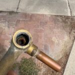 Close-up of eroded shower valve seat inside removed brass body showing stripped sealing surface from Sandy job