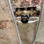 Black valve housing open on brass Grohe body after green plunger removed during Sandy UT shower work