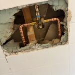 Brass Moen single-handle shower valve body plumbed with copper elbows inside tiled wall opening in Sandy Utah