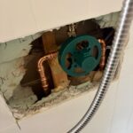 Green Moen pressure-balance shower valve rough-in mounted in opened tile wall with new copper in Sandy Utah
