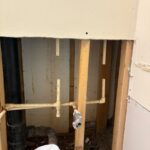 Remaining cream CPVC stubs and metal angle stop inside opened wall before full PEX swap in Sandy UT