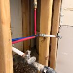 Close view of PEX tee, copper stubs, and two chrome quarter-turn valves mounted on studs in Sandy UT