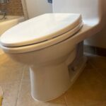 White toilet base on tile floor after finish caulk prep and seal work in a Millcreek Utah bathroom.