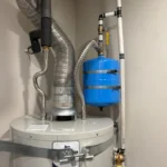 Top of Bradford White tank with draft hood, flexible vent, water lines, and blue expansion tank in North Salt Lake.