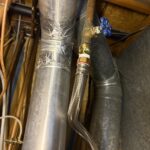 Brass shutoff with blue handle and braided supply on secondary water line near mechanical piping in West Jordan home.