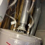 Water heater top with dual braided flex lines and shutoffs serving domestic supply in a West Jordan mechanical space.